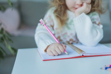 Küçük kıvırcık saçlı, mavi gözlü kız 4 yaşında, sıcacık bir evde. Mutlu bir çocuğun portresi. Ev okulu.