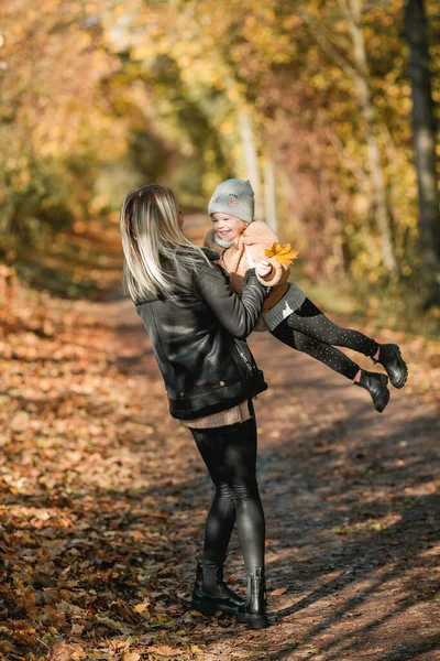 幸せな母親と娘が秋の公園を歩いています 暖かい服を着た美しい家族 — ストック写真