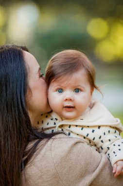 Güz parkında 7 aylık güzel bir kızı olan güzel, genç bir anne. Mutlu bir ailenin portresi..