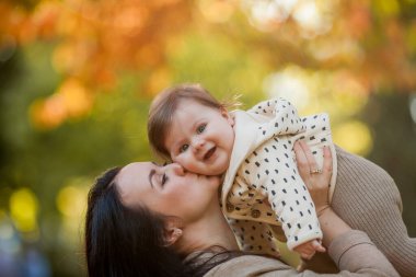 Güz parkında 7 aylık güzel bir kızı olan güzel, genç bir anne. Mutlu bir ailenin portresi..