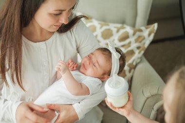 Emzirme. Güzel genç anne 2 aylık bebeğini biberonla besliyor. Bebek karışımı. Anne sütü. Annelik. Ev.