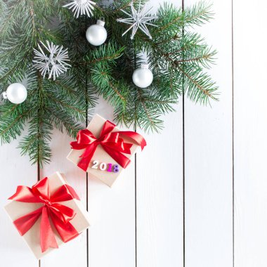 Kırmızı kurdele ve 2018 numaranın süslediği kutularda Noel hediyeleri, beyaz ahşap arka planda Noel ağacı, üst manzara.