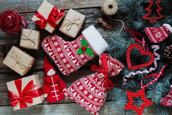 El işi kağıdında Noel hediyeleri, ahşap arka planda noel çantası, kırmızı desenli Noel ağacı, üst manzara.