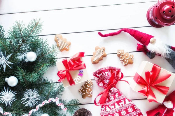 Noel hediyeleri, noel çantaları, zencefilli kurabiyeler, oyuncak Noel Baba, ahşap arka planda kırmızı lamba, dekorlu Noel ağacı, üst manzara