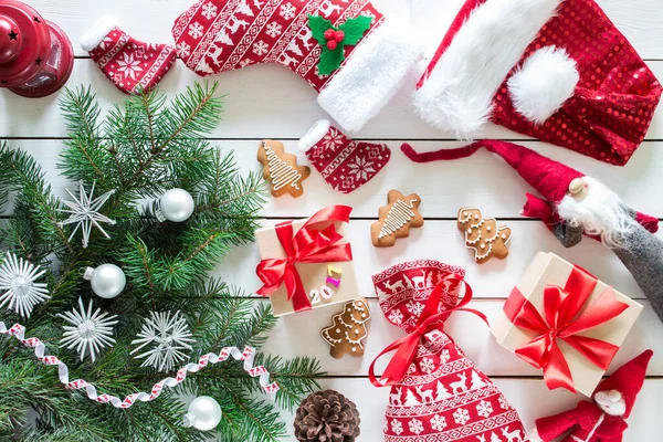 Noel hediyeleri, noel çantaları, zencefilli kurabiyeler, oyuncak Noel Baba, ahşap arka planda kırmızı lamba, dekorlu Noel ağacı, üst manzara