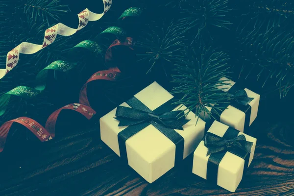 Ahşap arka planda Noel hediyeleri, renkli kurdeleli Noel ağacı.