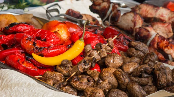 Izgara sebzeli tava, biber, mantar şiş ızgara et, pide, arka planda salata. Yemek festivali açık hava