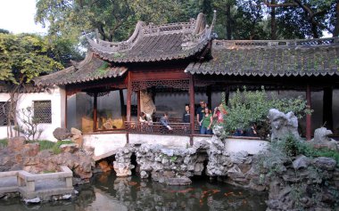 Yu Yuan Gardens, Şangay, Çin: Yu Garden 'daki insanlar küçük bir göletteki balığa bakıyorlar. Yu Yuan, Şangay 'da geleneksel bir Çin bahçesidir..