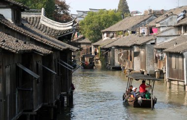 Wuzhen Su Kasabası, Zhejiang Eyaleti, Çin. Turistleri taşıyan küçük bir tekne eski kenti ve Wuzhen kanallarını geziyor..