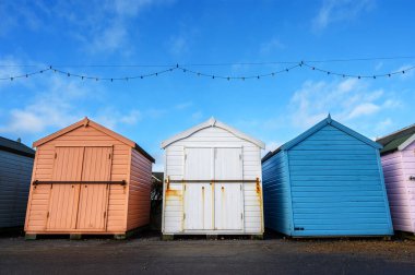Üç sahil kulübesi. Bu renkli plaj kulübeleri Felixstowe, Suffolk, İngiltere 'de bir İngiliz tatil köyünde geziniyor..