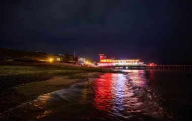 Felixstowe, Suffolk, UK: Geceleri Felixstowe iskelesi kırmızı ve sarı ışıklarla aydınlatılır. Sahilden rıhtımın manzarası Denizde yansımalarla.