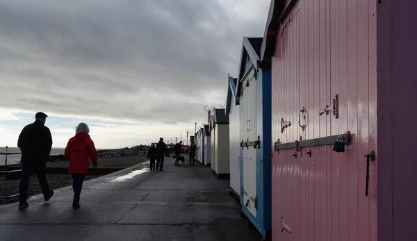 英国サフォーク州フェリックストウ 海に面したビーチ小屋のラインを過ぎ 寒い冬の日にフェリックストウの遊歩道を歩く人々 — ストック写真