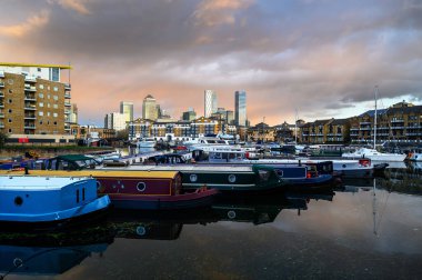 Limehouse, Londra, İngiltere: Limehouse Havzası, Doğu Londra 'nın rıhtım bölgesinde bir marina. Kanarya Rıhtımı 'nın arkasında yüksek binalar var. Birçok tekne ve mavna rıhtımda demirli..