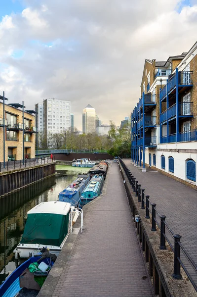 英国伦敦利默豪斯 Limehouse 船只停泊在伦敦东部码头地区利默豪斯盆地 Limehouse Basin 附近的一条运河上 侧边的公寓和后面的金丝雀码头 — 图库照片