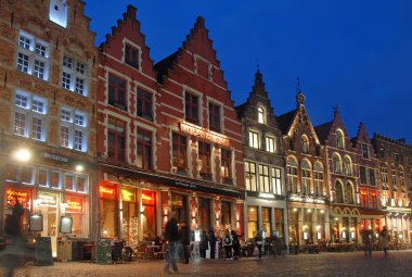 Brugge veya Bruges, West Flanders, Belçika: Brugge 'deki Pazar Meydanı' nda geleneksel eski binalar ve restoranlar. Yaşlı Bruges 'ün gece sahnesi.