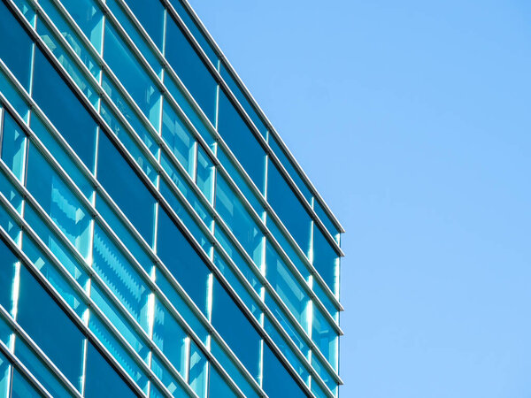 Modern glass office building against the clear blue sky.
