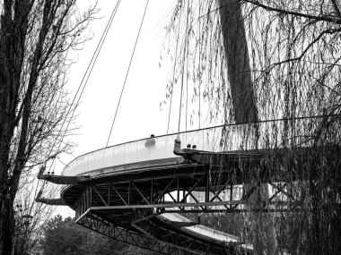 Parkta köprüde yürüyen bir adam. Romanya 'nın Bükreş kentinde Moghioros (Drumul Taberei) parkındaki tek renkli manzara.