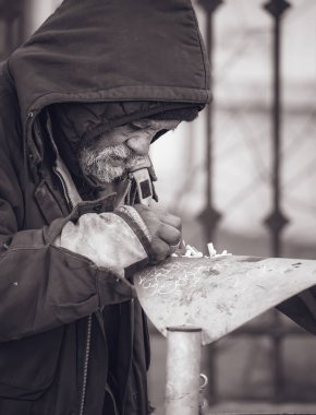 Bucharest, Romania - 02.04.2022: Homeless Man taking The Cigarette Butt from the garbage bin in the center of Bucharest.