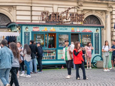 Bükreş, Romanya - 04.08.2022: Bükreş 'in eski şehir merkezinde bir krep kamyonunun önünde bir çok insanın oturduğu şehir manzarası.