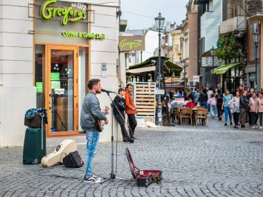 Bükreş, Romanya - 04.08.2022: Bükreş 'in eski şehir merkezinde gitar çalıp şarkı söyleyen genç sokak sanatçısı