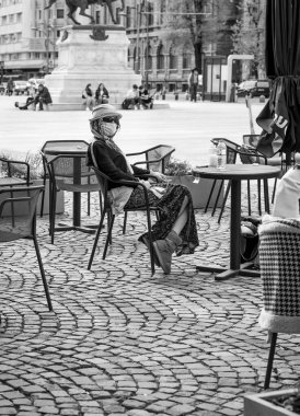 Bucharest, Romania - 04.08.2022: Unidentifiable woman sitting at an outdoor restaurant cafe in the old town center of Bucharest, Romania .