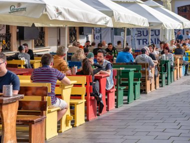 Bükreş, Romanya - 04.08.2022: Bükreş 'in merkezinde bir açık restoran ve kafede içki içen turistler ve yerel halk