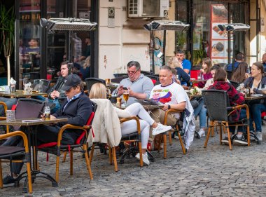 Bükreş, Romanya - 04.08.2022: Bükreş 'in merkezinde bir restoran ve kafede içki içen turistler ve yerel halk