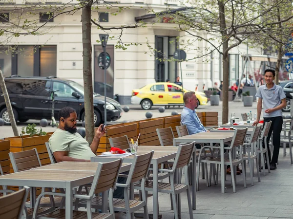 Bükreş, Romanya - 04.08.2022: Bükreş 'in merkezinde bir açık restoran ve kafede içki içen turistler ve yerel halk