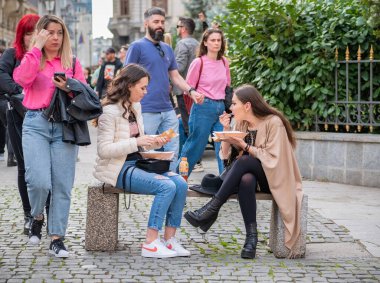 Bükreş, Romanya - 04.08.2022: Bükreş 'in eski şehir merkezinde bir bankta oturan iki güzel genç kız.