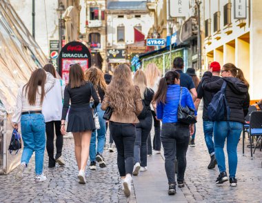 Bükreş, Romanya - 04.08.2022: Bükreş 'in eski kent merkezini ziyaret eden bir grup genç turist kızla arka manzara