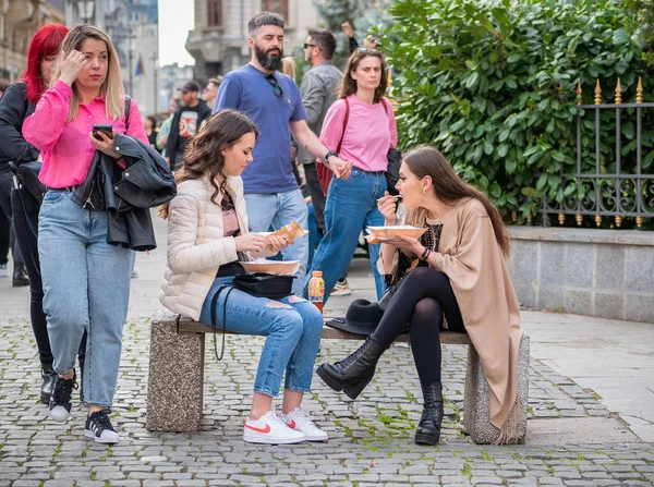 Bükreş, Romanya - 04.08.2022: Bükreş 'in eski şehir merkezinde bir bankta oturan iki güzel genç kız.