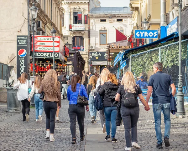 Bükreş, Romanya - 04.08.2022: Bükreş 'in eski kent merkezini ziyaret eden bir grup genç turist kızla arka manzara