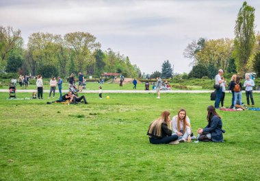 Bükreş, Romanya - 04,15,2022: Bükreş 'teki KIng MIhai I parkında (Herestrau) insanlar rahatlıyor ve çimlerde eğleniyorlar