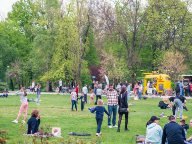Bükreş, Romanya - 04,15,2022: Bükreş 'teki KIng MIhai I parkında (Herestrau) insanlar rahatlıyor ve çimlerde eğleniyorlar