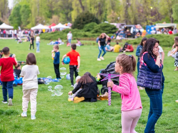 Bükreş, Romanya - 04,15,2022: Bükreş 'teki KIng MIhai I park (Herestrau) çimlerinde oynayan ve eğlenen çocuklar