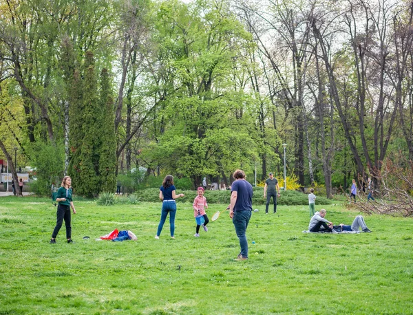 Bükreş, Romanya - 04,15,2022: Bükreş 'teki KIng MIhai I parkında (Herestrau) insanlar rahatlıyor ve çimlerde eğleniyorlar
