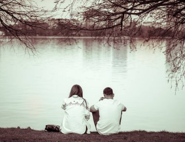 Gölün kenarında oturan bir çiftin klasik monokrom fotoğrafı.