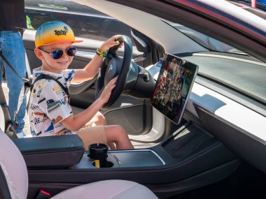 Bükreş, Romanya - 05.20.2022: Tesla Model 3 'te sürücü koltuğunda mutlu genç yetişkin.