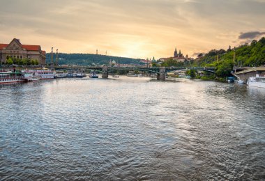 Prague, Czech Republic - June 2022: Beautiful view at sunset with Cech Bridge (Cechuv most) from Vltava river with Prague castle in the distance.