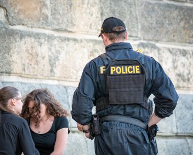 Prague, Czech Republic - June 2022: Police forces checking the ID of a young girl sitting on a bench on Naplavka along the Vltava river, in Prague