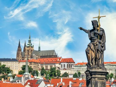 Statue of a saint on Charles Bridge pointing towards Prague Castel in Czech Republic