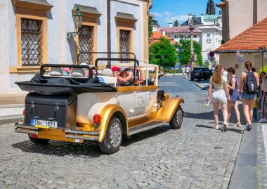 Prag, Çek Cumhuriyeti - Haziran 2022: Eski Prag kentinin kaldırım taşı caddelerinde eski bir retro arabada özel bir turun tadını çıkaran turistler