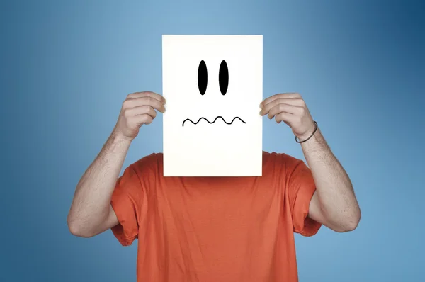 Boy showing a blank paper with a disgusted emoticon — Stock Photo, Image