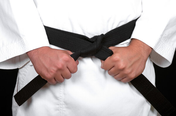 karate man tying the knot to his black belt