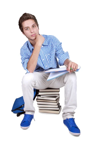Estudante adolescente sentado em uma pilha de seus livros didáticos — Fotografia de Stock