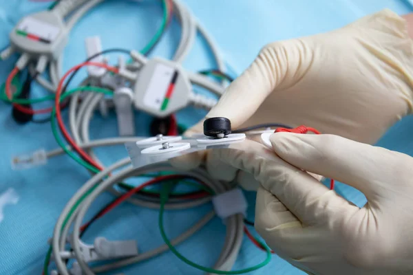 Dokter tangan menghubungkan elektroda untuk perangkat stimulasi neuromuskular Stok Foto