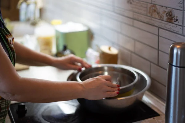 Руки пожилой женщины держат чашу на кухне. Женщина готовит что-то на кухне вечером.. — стоковое фото