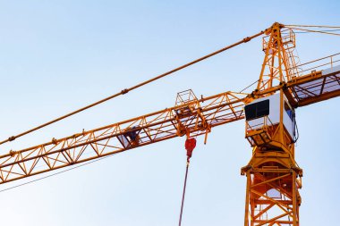 Mavi arka planda turuncu renkli bina vincinin fotoğrafı.