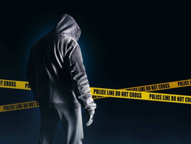 Korku filmi. Siyah kapüşonlu bir sapık ve koyu mavi arka planda polis çizgileri olan bir giysi..