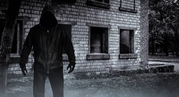 写真の恐怖見知らぬストーカー男で黒フードと服で放棄された建物の背景 — ストック写真